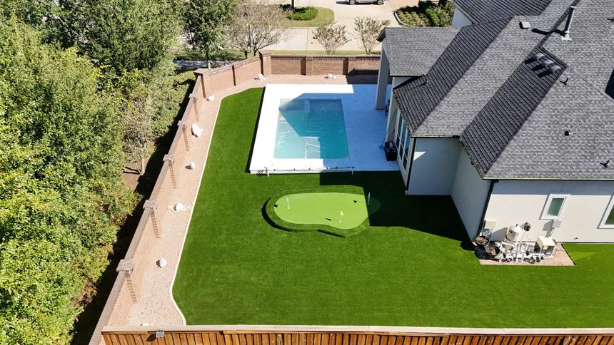 Custom backyard putting green beside a pool